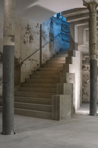 Escalera de hormigón con iluminación azul: Escaleras de cemento con barandillas metálicas en un espacio industrial, iluminadas con luz tenue azul.
