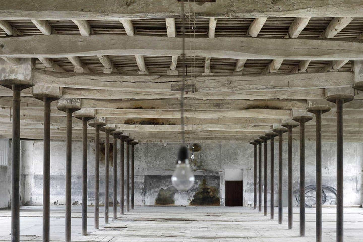 Techo de madera con estructura de hierro en fábrica abandonada: Espacio amplio con vigas y columnas alineadas en un entorno industrial.
