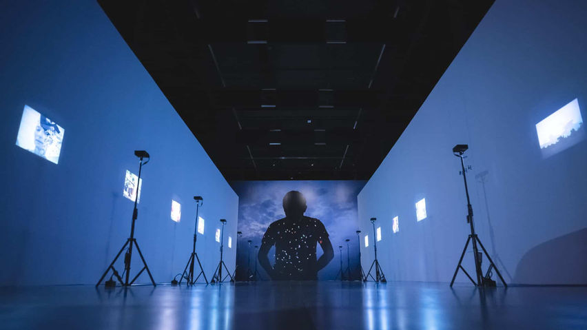 Sala oscura con proyecciones digitales y pantallas interactivas, ideal para eventos tecnológicos e inmersivos.
