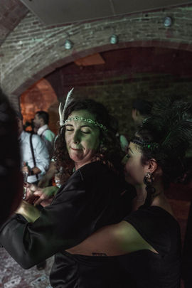 Pareja vestida de los años 20 sonriendo en fiesta corporativa Gatsby, disfrutando de la ambientación retro.
