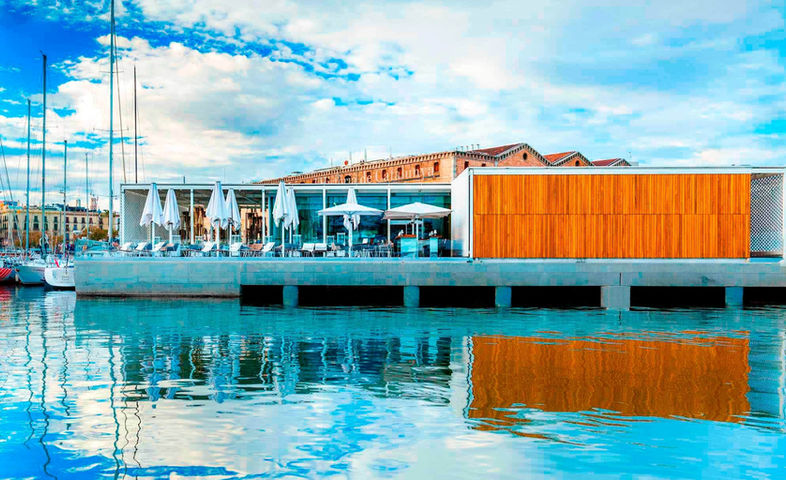 Vista diurna del restaurante flotante con estructura moderna sobre el agua – arquitectura innovadora en entorno marino.
