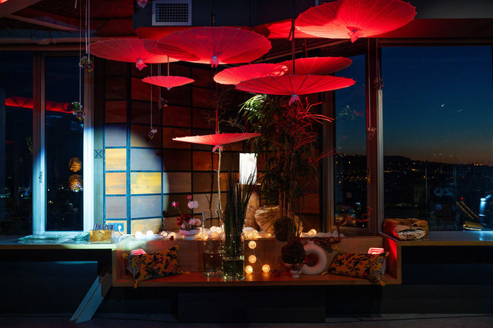 Terraza con iluminación roja y vistas nocturnas: Espacio exterior con sombrillas decorativas y una atmósfera acogedora con luces cálidas.