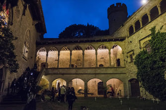 Castillo iluminado de noche con arcos medievales y torres – Vista nocturna de un castillo histórico con arcos de piedra iluminados, evocando una atmósfera medieval.