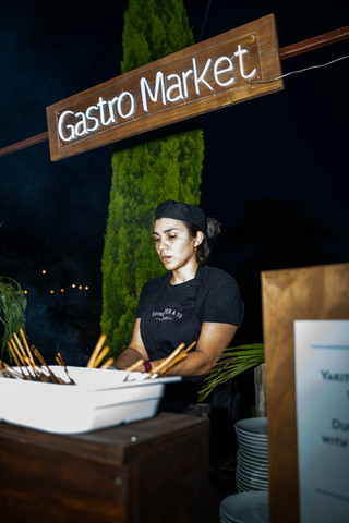 Chef preparando brochetas en un stand de comida: Puesto de gastronomía con iluminación nocturna.
