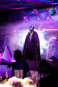 Escenario inmersivo en Integrated Systems Europe (ISE) Barcelona con temática futurista – Personaje enmascarado con capa oscura sobre un escenario iluminado con neón, humo y estructuras geométricas de colores vibrantes.