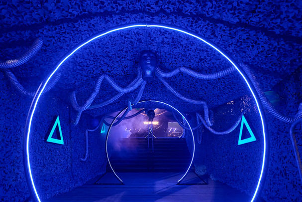 Pasillo temático con luces azules y estructura futurista en una fiesta exclusiva de empresa.
