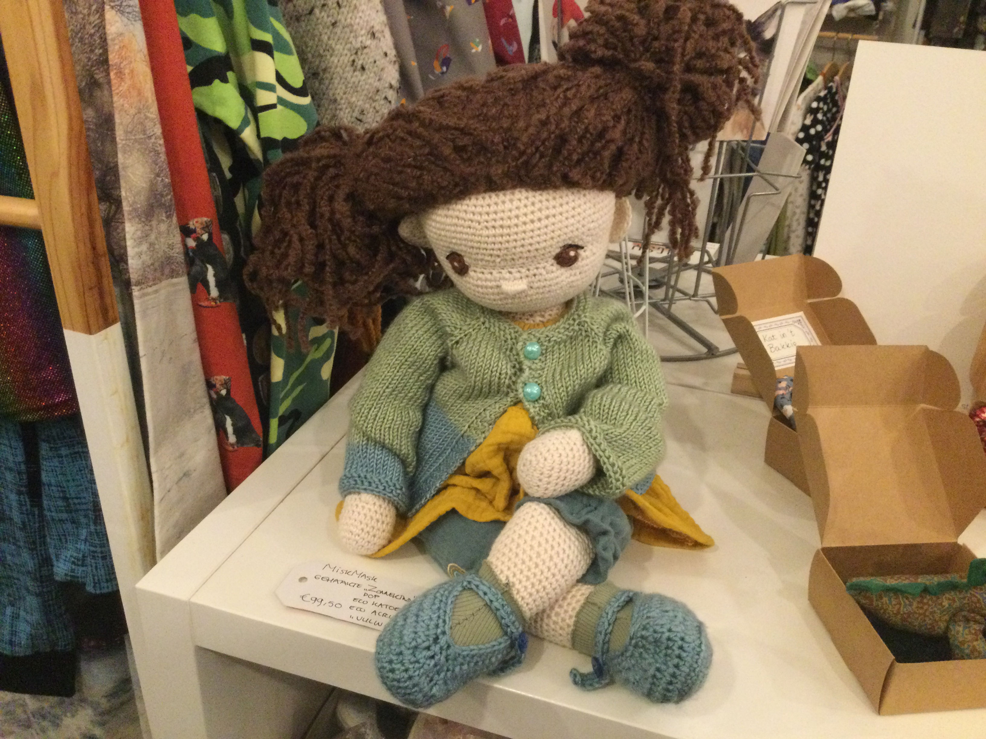 Gehaakte Zonnekindpop met bruin haar en blauwe schoenen op witte tafel, www.miskmask.nl