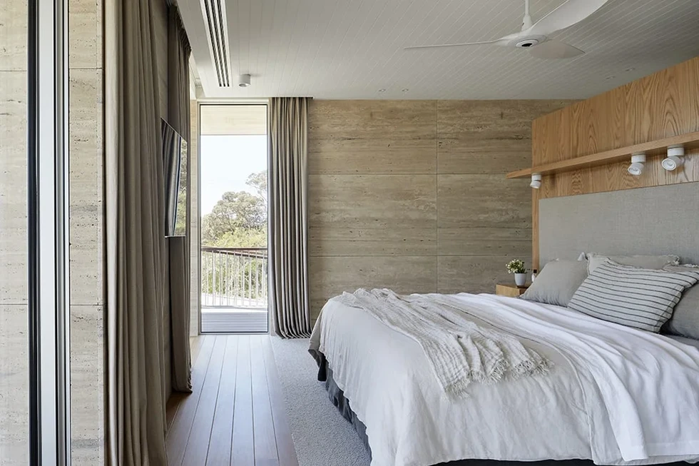 Bedroom with natural light and travertine walls inside Sand Dune Sanctuary by Hindley & Co.