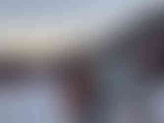 two friends laughing on a ski season in front of a sunset