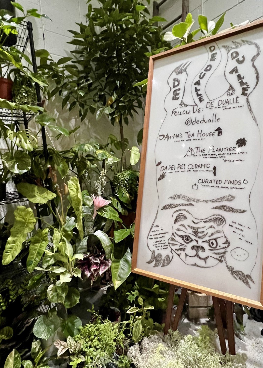 De Duallè's illustrated signage, surrounded by plants.