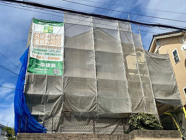 外壁塗装専門店・一条建装の看板シートが貼ってある足場が立っている川西市の住宅。