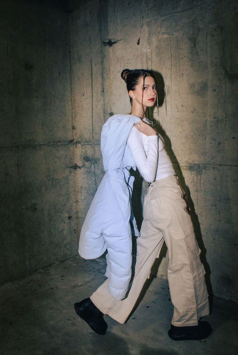 A model styled by fashion marketing students poses in front of a concrete wall.
