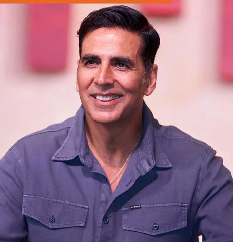 Smiling man in a red shirt against a gray background. The mood is cheerful and positive with no visible text.