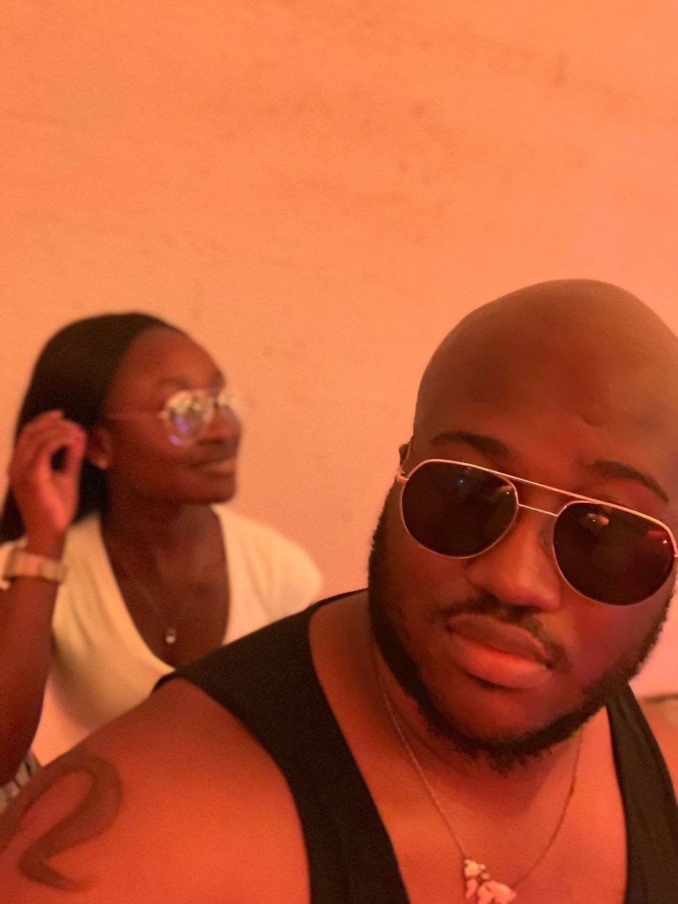 Yasmine and her partner in front of a salmon colored wall taking a selfie of the two of them.