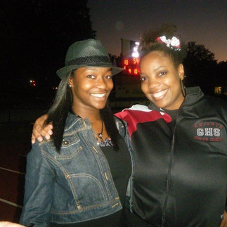 Image of two Black girls smiling at a football game 