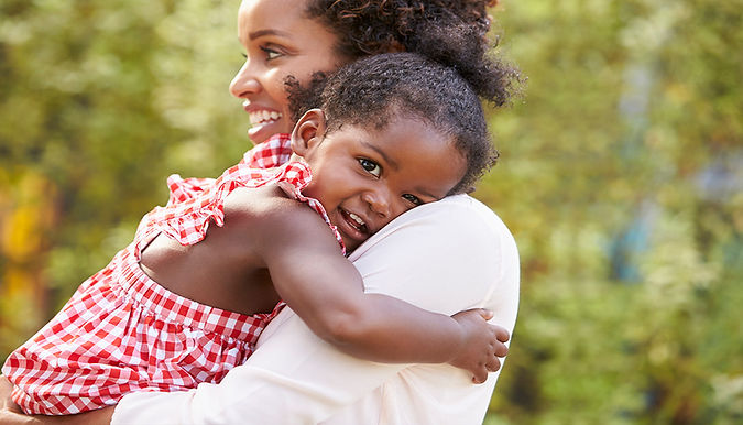 African American mom smiling holding her baby against her shoulder