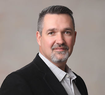 Todd wearing a suit jacket, smiling into camera.