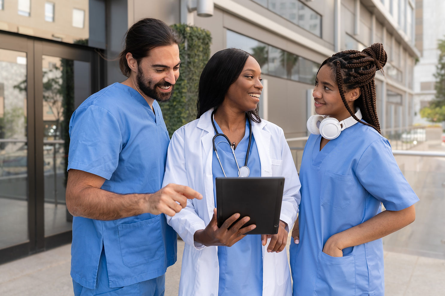 Multiracial Doctors and nurses using a tablet and discussing patient information outside h
