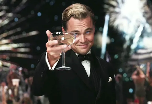 Leonardo Decaprio drinking from a 1920s champagne glass with fireworks in the background.