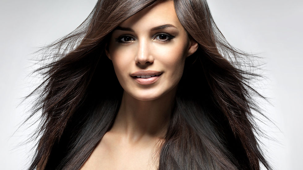 Woman with long, flowing dark hair smiles at the camera. She's wearing a white top against a gray background, conveying elegance.