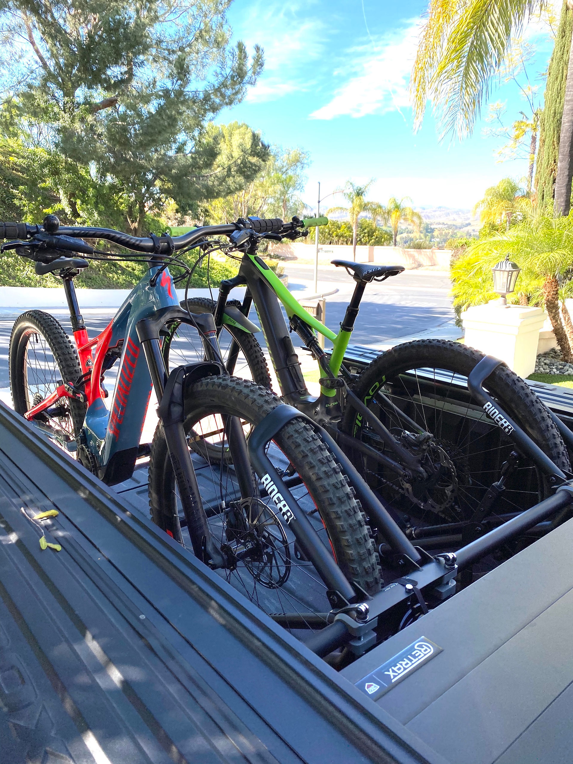 Two RIDE88 truck bike racks installed in a pickup truck holding two mountain bikes, one with the front wheel mounted and one with the rear wheel mounted.