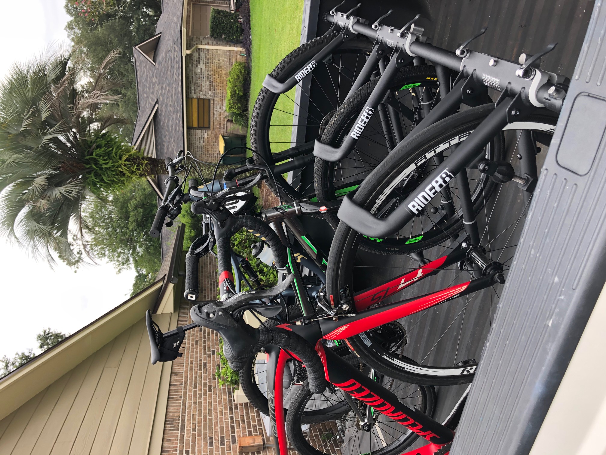 Three RIDE88 truck bike racks installed on a pickup truck holding three bikes on their front wheels. Two are mountain bikes and one is a skinny tire road bike.