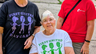 Three smiling women wearing "First United Daycare" t-shirts posing together at the event.
