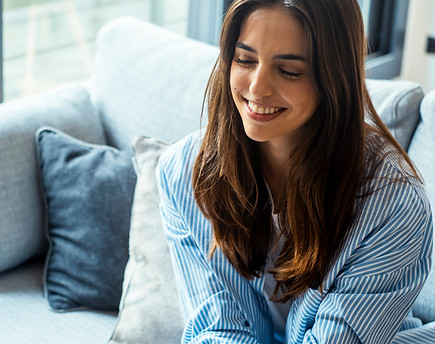 Female psychological therapy session with girl sitting indoors on sofa smiling cheerfully.