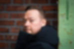 Image of a man in front of a brick wall.