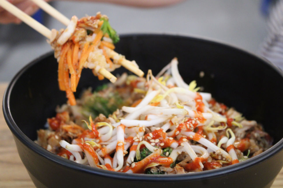 Chopsticks lifting mixed dish with carrots, sprouts, and sauce