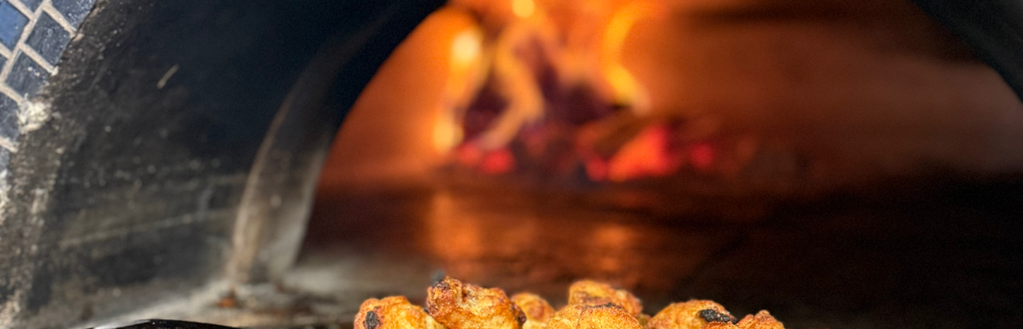 Chicken wings cooking in a brick oven