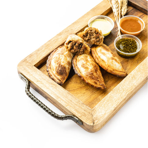 Empanadas with dipping sauces on a wooden tray