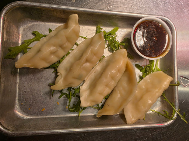 Four dumplings with dipping sauce and greens