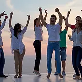 group of happy young people dancing and have fun on party in modern home bacony with sunset and ocean in background.webp