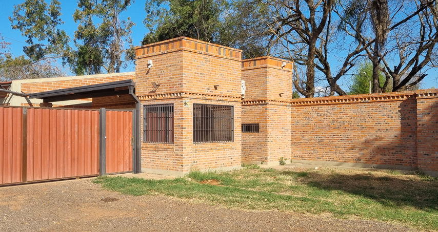 “Garita de ingreso y oficinas del depósito en Luque con fachada de ladrillo y portón rojo”