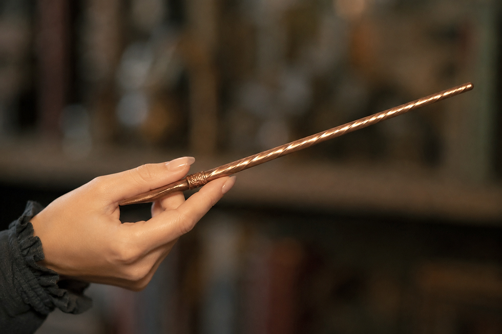 hand holding a copper coloured wand.png