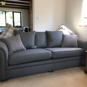Grey sofa in room with pillows and natural light from window.