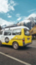 Yellow and white van driving on road with snow mountains of New Zealand in the background. Lifestyle photographer Munich