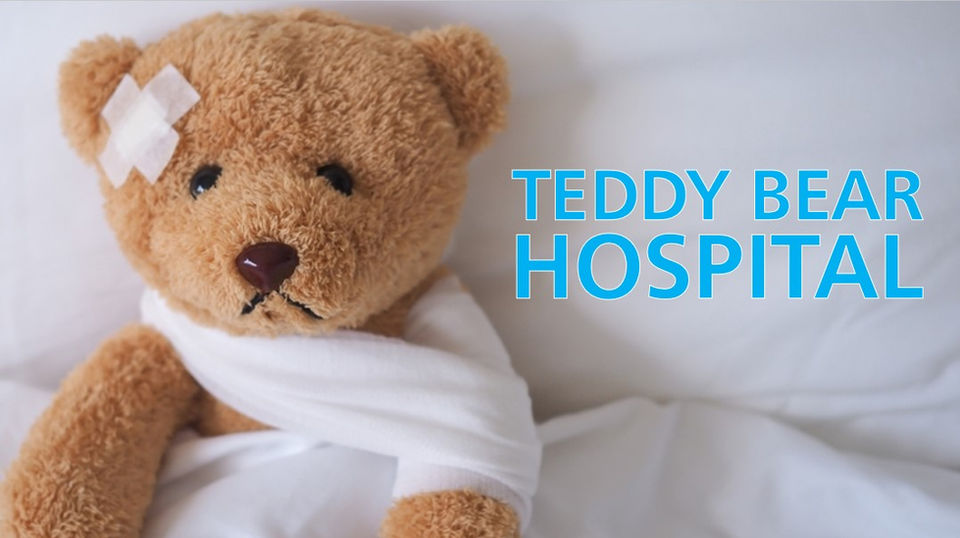Teddy Bear Hospital title - A bandaged teddy bear in bed