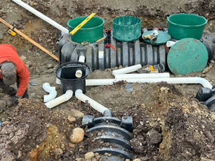 Excavator installing an Infiltrator chamber drain field in rainy conditions on a rural property along Findlay Lake Road West near Terrace, BC.