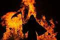 A grim reaper silhouette stands in front of a wall of flames.