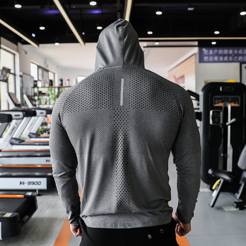 Costas de homem usando camiseta fitness cinza com capuz em academia