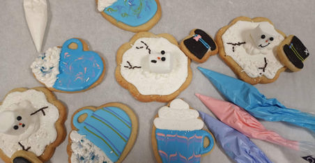 Decorated cookies with blue icing and white icing on a white surface.