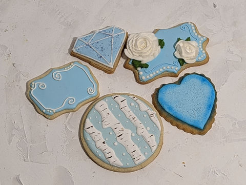 Six blue iced cookies with white designs, including a diamond cookie.