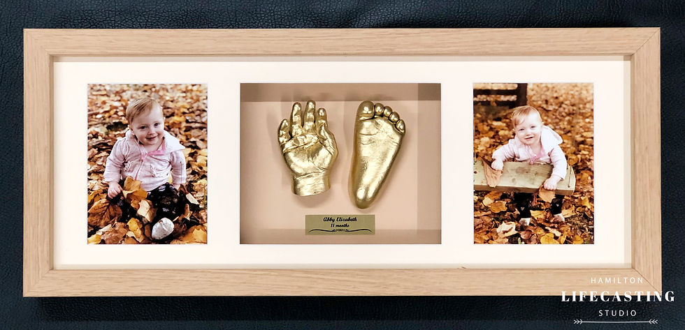 Bright gold toddler hand and foot sculptures in teak frame