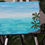 Thumbnail: The canvas painting on an easel, with the artist adding final touches to the ocean and palm tree design.