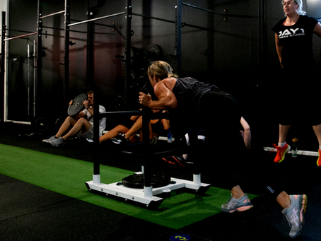 A fit woman pushing a heavy gym sled