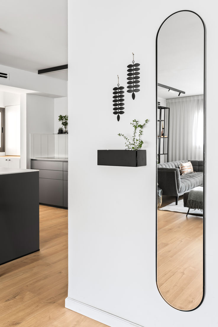 מבואת כניסה מעוצבת ויפה עם מראה אובלית וקופסת ברזל שחורה להנחת מפתחות ודואר