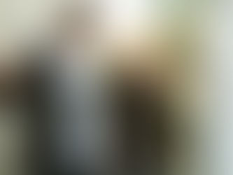 A couple, with the man in the foreground, apparently arguing in a lane between the house and a fence, with trees in the background.