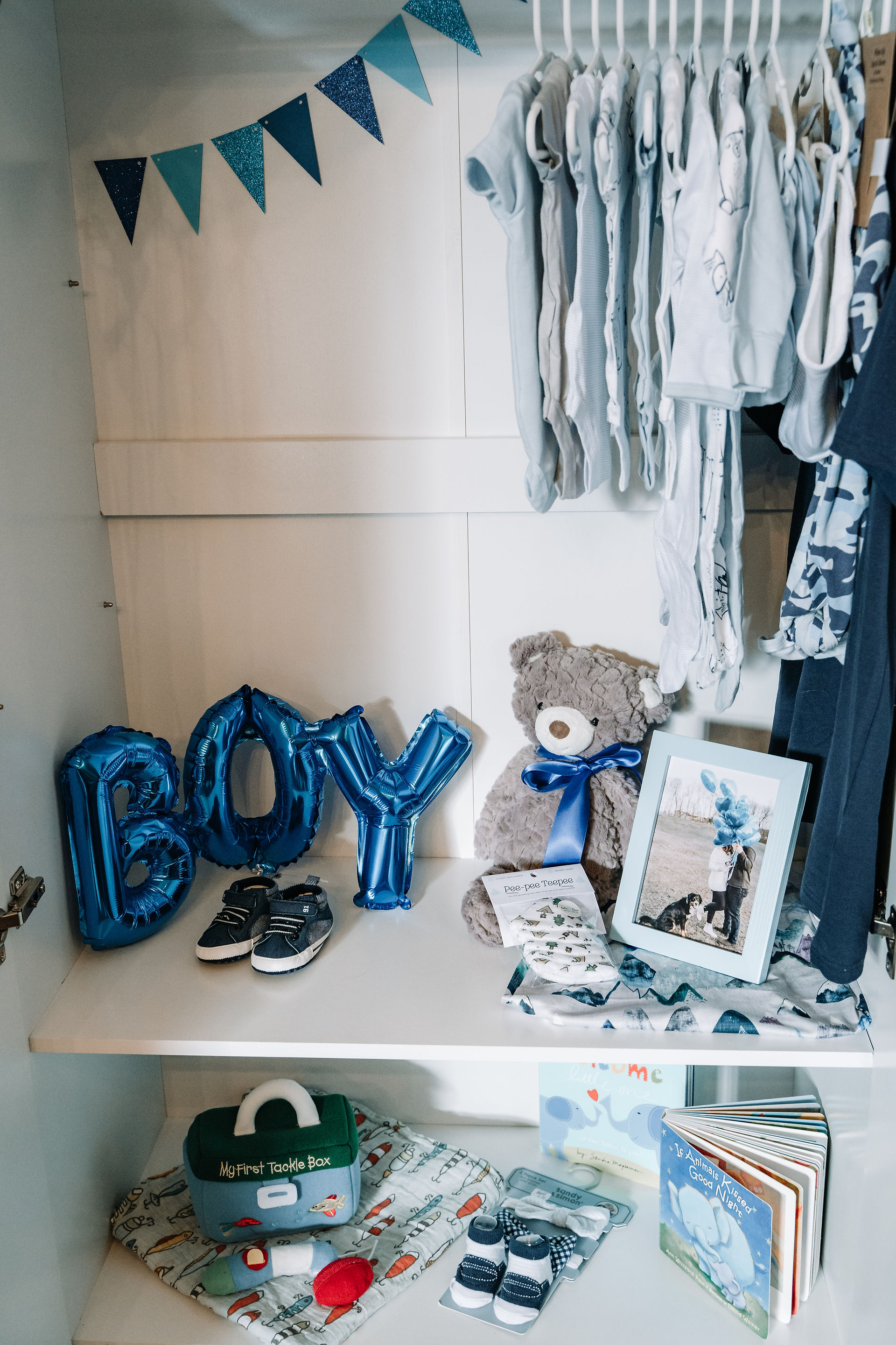 the inside of a cabinet full of baby boy clothes and toys